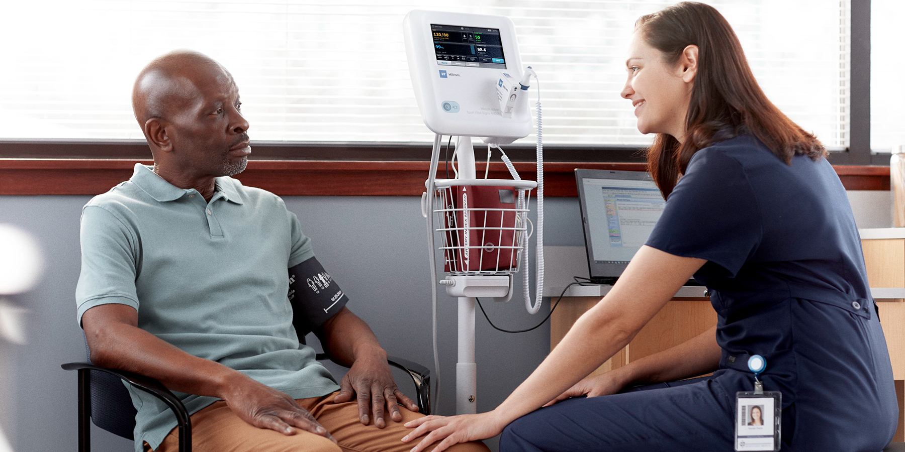 Female clinician talks to male patient after a blood pressure exam. 